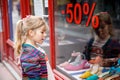 Little Girl looks at the window near the shopping center. Adorable happy child looking on shoes in store window. Royalty Free Stock Photo