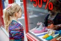 Little Girl looks at the window near the shopping center. Adorable happy child looking on shoes in store window. Royalty Free Stock Photo