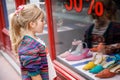 Little Girl looks at the window near the shopping center. Adorable happy child looking on shoes in store window. Royalty Free Stock Photo