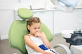 Little girl looks worried with fear closes mouth with handssitting in a dental chair. Visiting dentist with children