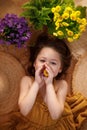 Little girl lying on background from straw hats holding flowers in hands, summer and travel feeling concept