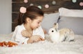 Girl lying on the bed and feeding the rabbit Royalty Free Stock Photo