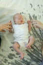 Little girl lying on the bed on her back. The baby is holding mom and dad`s hands. Family ties concept Royalty Free Stock Photo