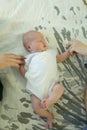 Little girl lying on the bed on her back. The baby is holding mom and dad`s hands. Family ties concept Royalty Free Stock Photo