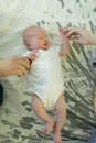 Little girl lying on the bed on her back. The baby is holding mom and dad`s hands. Family ties concept Royalty Free Stock Photo