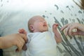 Little girl lying on the bed on her back. The baby is holding mom and dad`s hands. Family ties concept Royalty Free Stock Photo