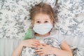Little girl lying in bed in medical mask. dinosaur Royalty Free Stock Photo