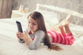 Little girl lying in bed with a remote control TV Royalty Free Stock Photo