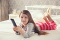 Little girl lying in bed with a remote control TV Royalty Free Stock Photo