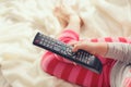 Little girl lying in bed with a remote control TV Royalty Free Stock Photo