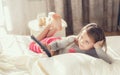 Little girl lying in bed with a remote control TV Royalty Free Stock Photo