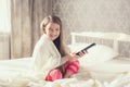 Little girl lying in bed with a remote control TV Royalty Free Stock Photo