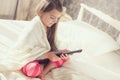 Little girl lying in bed with a remote control TV Royalty Free Stock Photo