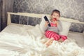 Little girl lying in bed with a remote control TV Royalty Free Stock Photo