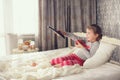 Little girl lying in bed with a remote control TV Royalty Free Stock Photo