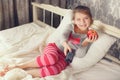 Little girl lying in bed with a remote control TV Royalty Free Stock Photo