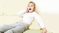 Little girl is lying on the couch in the living room and talking on the phone. expresses the emotion of surprise. In the interior Royalty Free Stock Photo