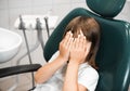 little girl lying in a dentist chair and covering her eyes, being afraid of the checkup at the dentists Royalty Free Stock Photo