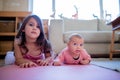 Little Girl Lying Down Next to her Baby Sister on a Pink Mat Royalty Free Stock Photo