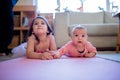 Little Girl Lying Down Next to her Baby Sister on a Pink Rug Royalty Free Stock Photo