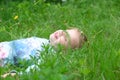 Little girl lying on grass lawn smiling. Summer fun outdoors. Happy child enjoying on grass field and dreaming Royalty Free Stock Photo