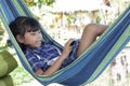 Little girl lying in the hammock and playing games on mobile phones. Royalty Free Stock Photo