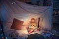 Little girl lying in a teepee, playing with the flashlight Royalty Free Stock Photo
