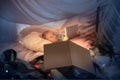 Little girl lying in a teepee, playing with the flashlight Royalty Free Stock Photo