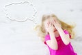 Little girl lying on white wooden floor with a speech bubble above her head Royalty Free Stock Photo