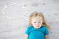 Little girl lying on white wooden floor with a speech bubble above her head Royalty Free Stock Photo