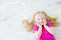 Little girl lying on white wooden floor with a speech bubble above her head Royalty Free Stock Photo