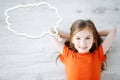 Little girl lying on white wooden floor with a speech bubble above her head Royalty Free Stock Photo