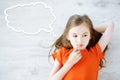 Little girl lying on white wooden floor with a speech bubble above her head Royalty Free Stock Photo