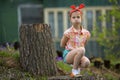 Little girl makes faces at the camera while sitting near country house.