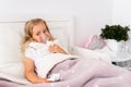 Little girl makes inhalation with a nebulizer in the house lying in bed in white room. Child asthma inhaler, nebulizer Royalty Free Stock Photo