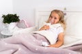 Little girl makes inhalation with a nebulizer in the house lying in bed in white room. Child asthma inhaler, nebulizer Royalty Free Stock Photo