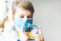 Little girl makes injection. Cute child with medical mask playing doctor, holding syringe with vaccine. Coronavirus Royalty Free Stock Photo