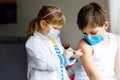 Little girl makes injection to brother, school kid boy. Children, siblings with medical mask playing doctor, holding Royalty Free Stock Photo