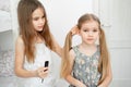 Little girl makes ponytails of her younger sister