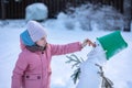 Little girl makes snowman on winter frosty day. Child makes nose out of carrot. Royalty Free Stock Photo