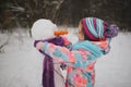 Girl makes snowman in winter park