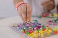 Little girl making beaded jewelry at table, closeup Royalty Free Stock Photo