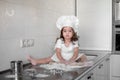 Little girl making dough and cookies in kitchen