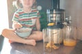 Little girl making fresh juice on the table in home kitchen. Focus on juicer Royalty Free Stock Photo