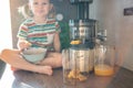 Little girl making fresh juice on the table in home kitchen. Focus on juicer Royalty Free Stock Photo