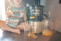 Little girl making fresh juice on the table in home kitchen. Focus on juicer Royalty Free Stock Photo