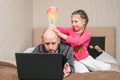 A little girl is making fun of dad. A child prevents a man from working on a laptop in his bedroom. The daughter puts the slinky