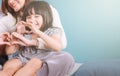 Little girl making heart shape sit in mom lap.