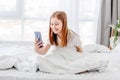 Girl with smartphone in the bed Royalty Free Stock Photo