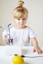 Little girl in a mask for inhalations, making inhalation with nebulizer at home inhaler on the table Royalty Free Stock Photo